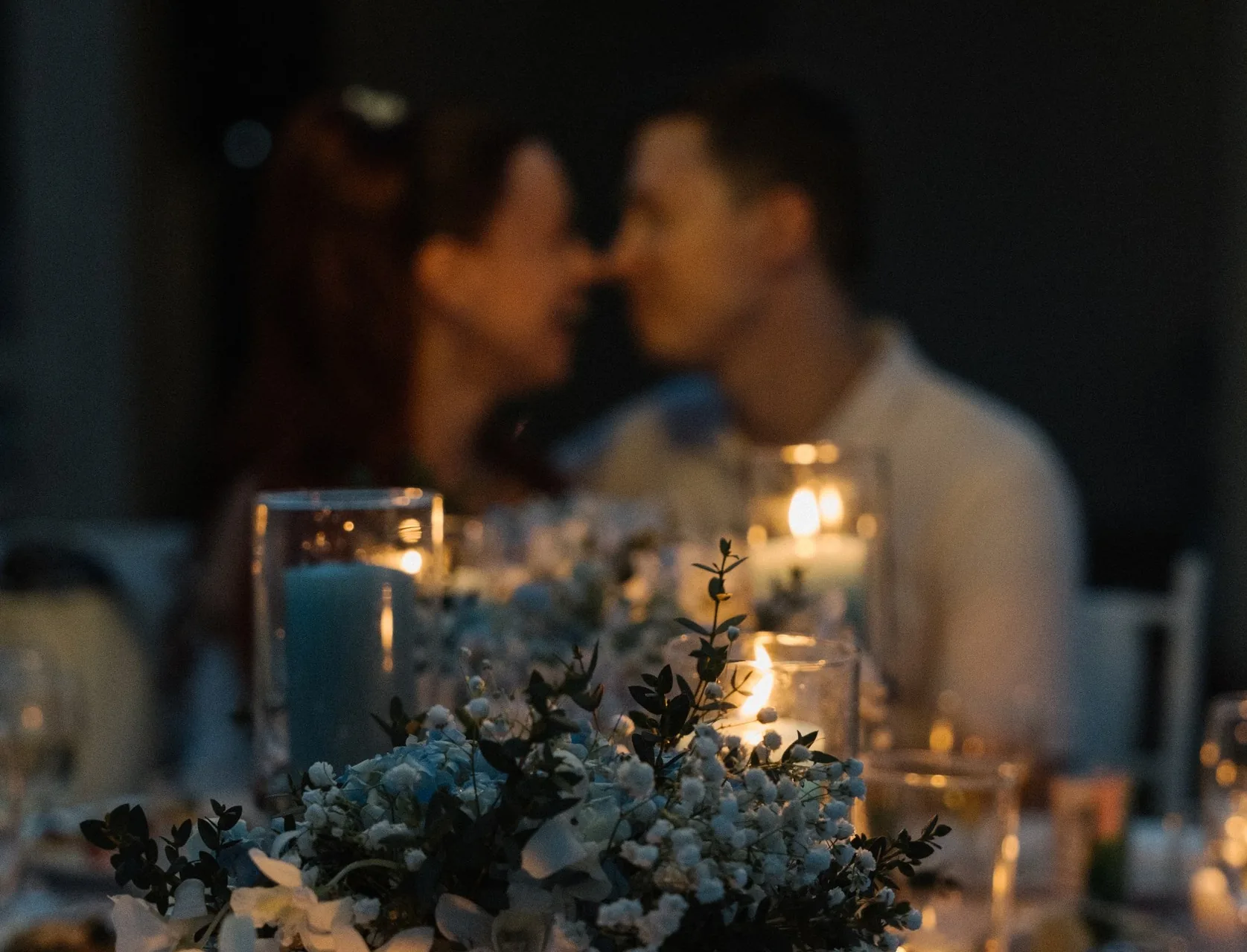 A candlelit dinner scene with a couple softly blurred in the background