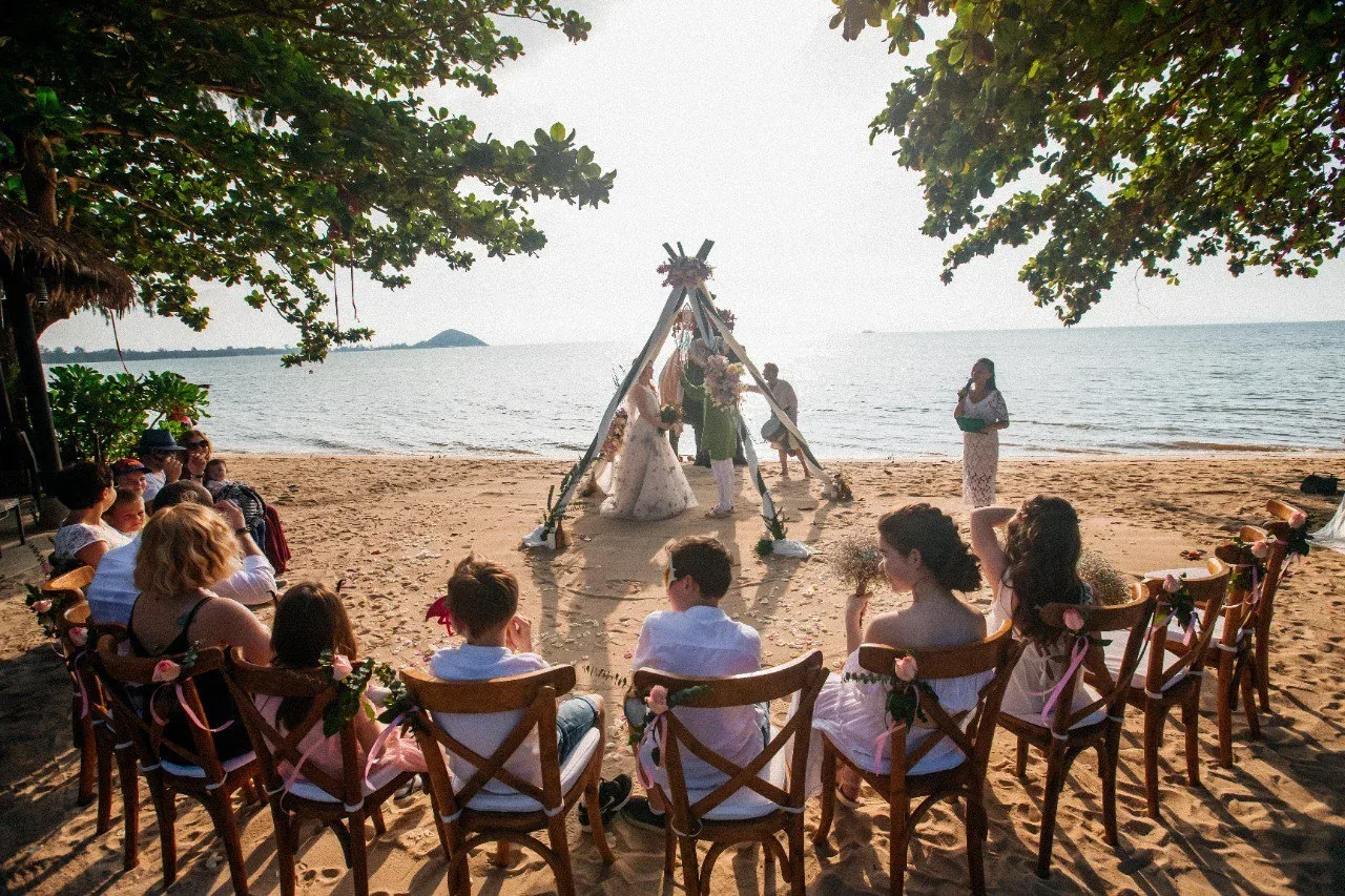 Beach wedding ceremony framed by trees and sea